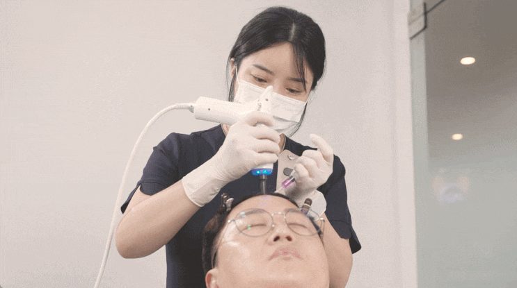 의료진이 기기를 이용해 두피에 재생 주사를 시술하는 장면