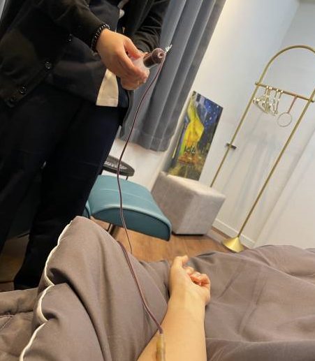 의료진이 정맥주사 라인을 점검하는 동안 환자가 침대에 누워 있는 수액실 장면