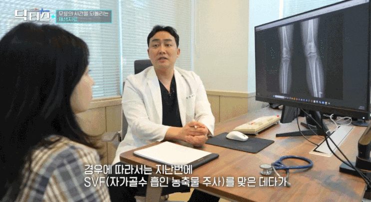흰 가운을 입은 의사가 무릎 X-ray 영상이 띄워진 모니터 옆에서 환자와 마주 앉아 상담하는 장면